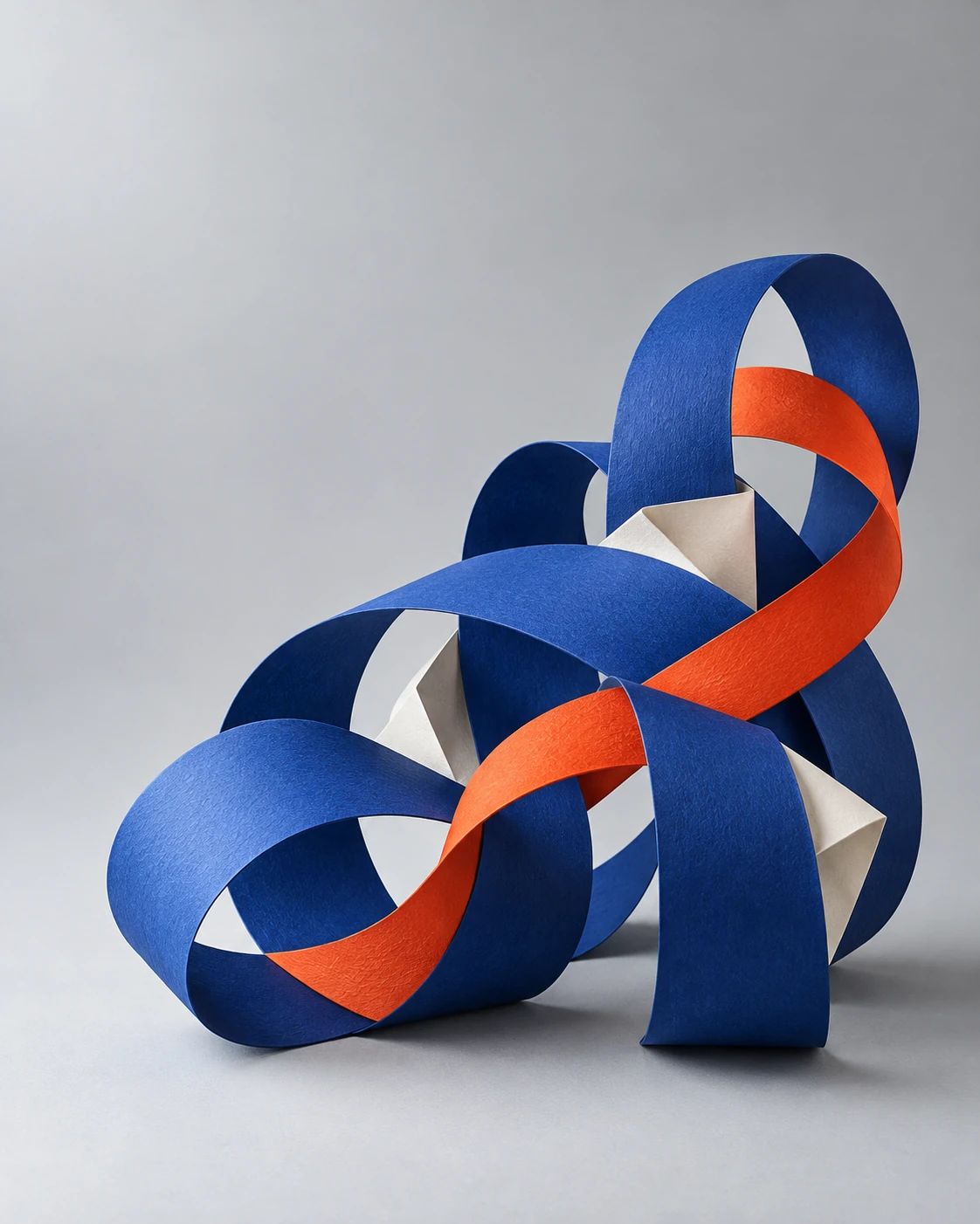 Interwoven blue and orange paper ribbons forming a connected sculpture.